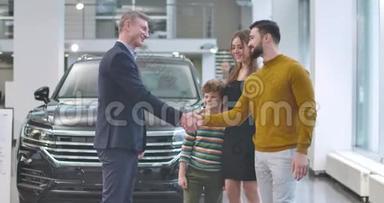 高加索汽车经销商站在新车前，祝贺年轻家庭购买汽车。人